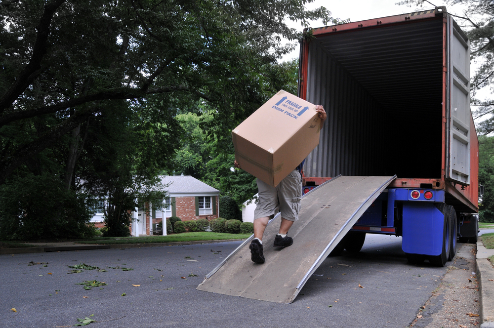man loading large box into truck